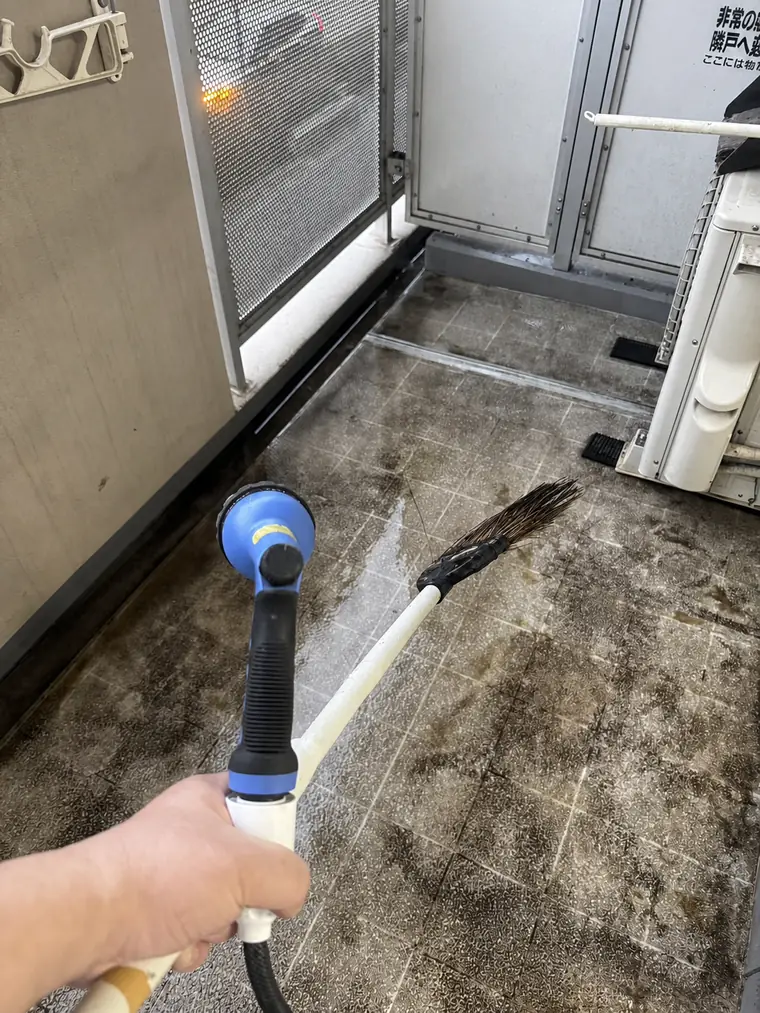 西宮市の家財整理現場でベランダの床面を洗浄している様子